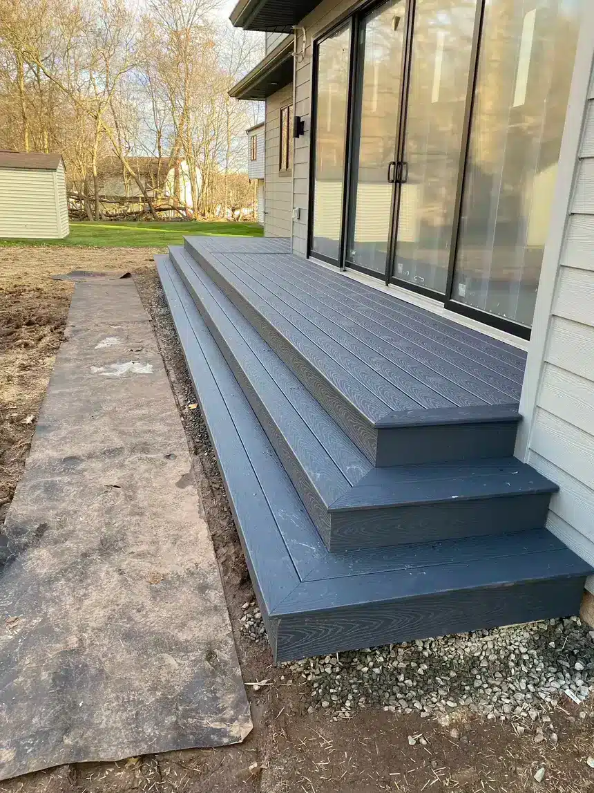 Gray composite deck steps leading to sliding glass doors on a modern home.