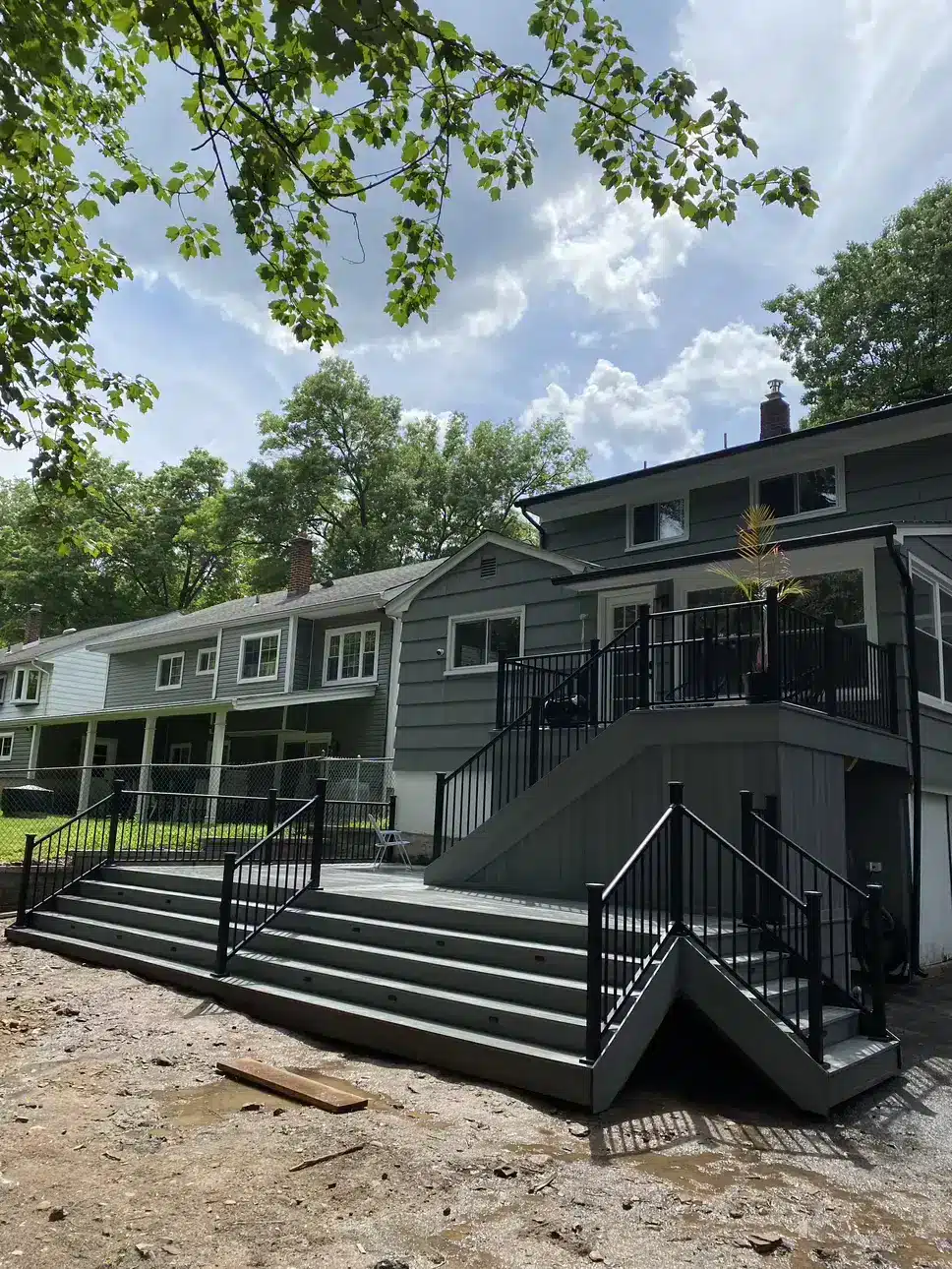 Multi-level deck with wide stairs, black metal railings, and a modern gray finish.