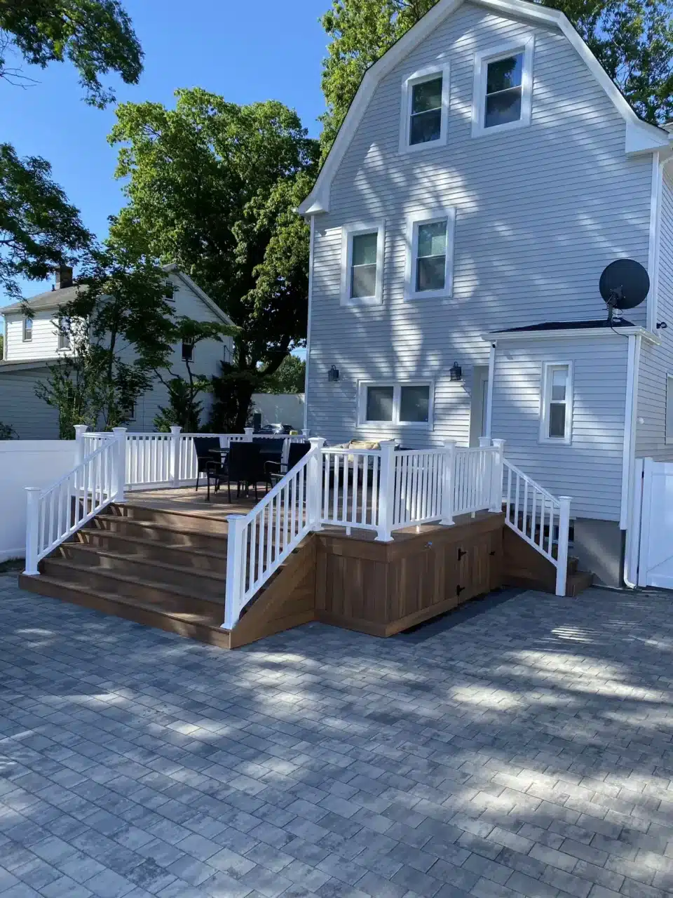 Elevated brown composite deck with white railings and built-in storage.