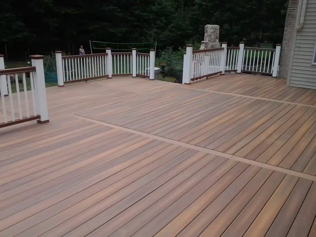 Spacious composite deck with a warm wood-tone finish, featuring white and brown railings for a stylish and inviting outdoor space.