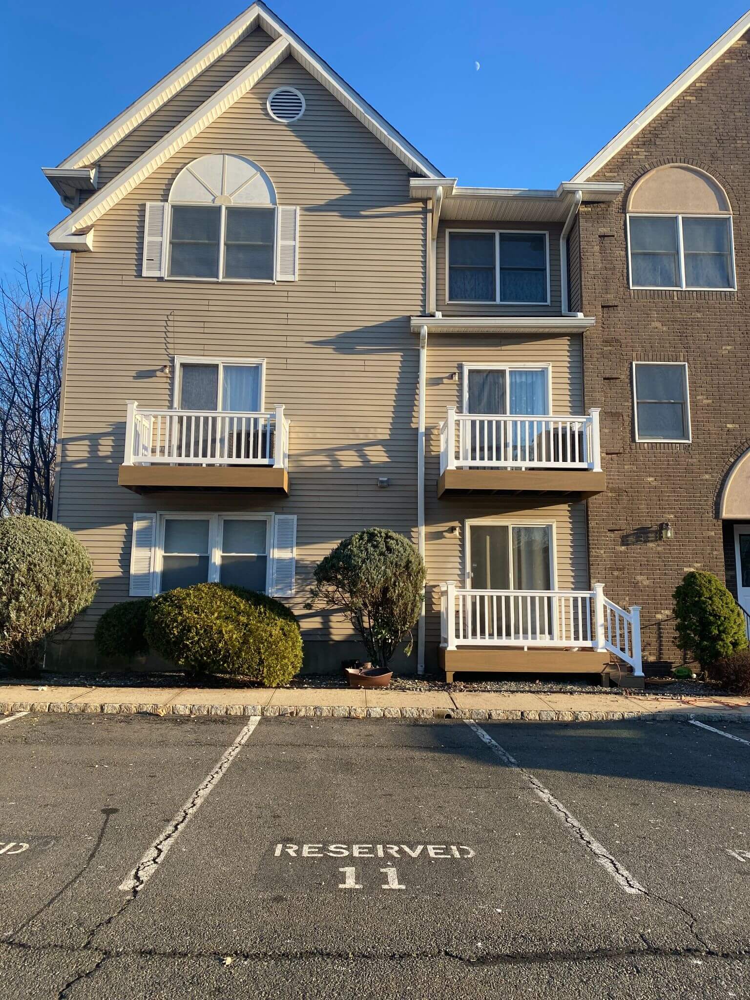 Exterior view of a residential building with new white vinyl railings on new balcony decks.