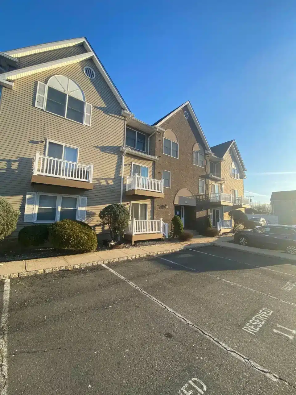 Residential building with new balcony decks that feature white vinyl railing that replaced aging wooden railing.