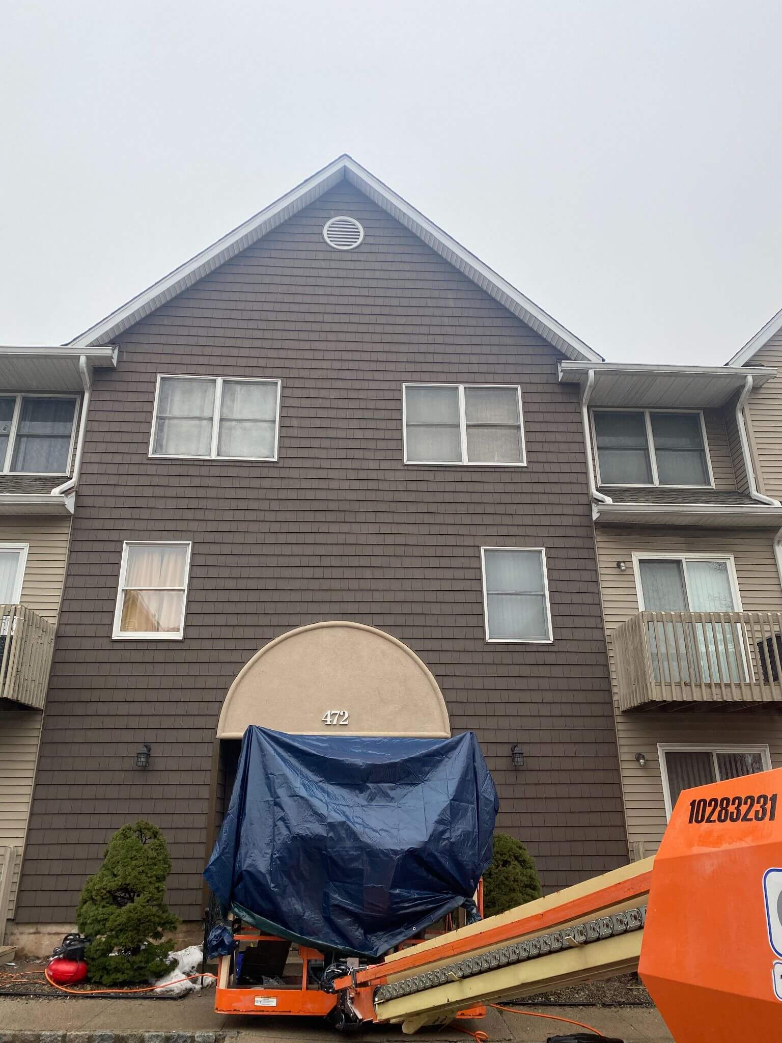 Work in progress with equipment in front of a building where brick facade will replace siding