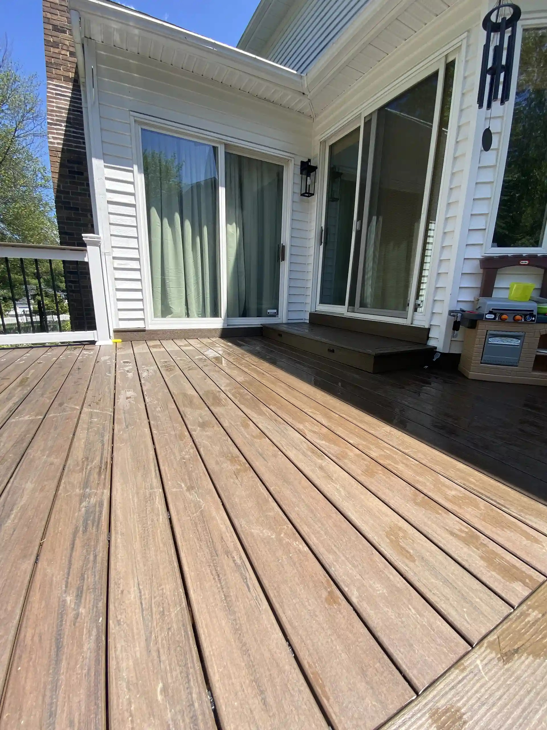 Wood deck with sliding glass doors, a wind chime, and a children's play kitchen.