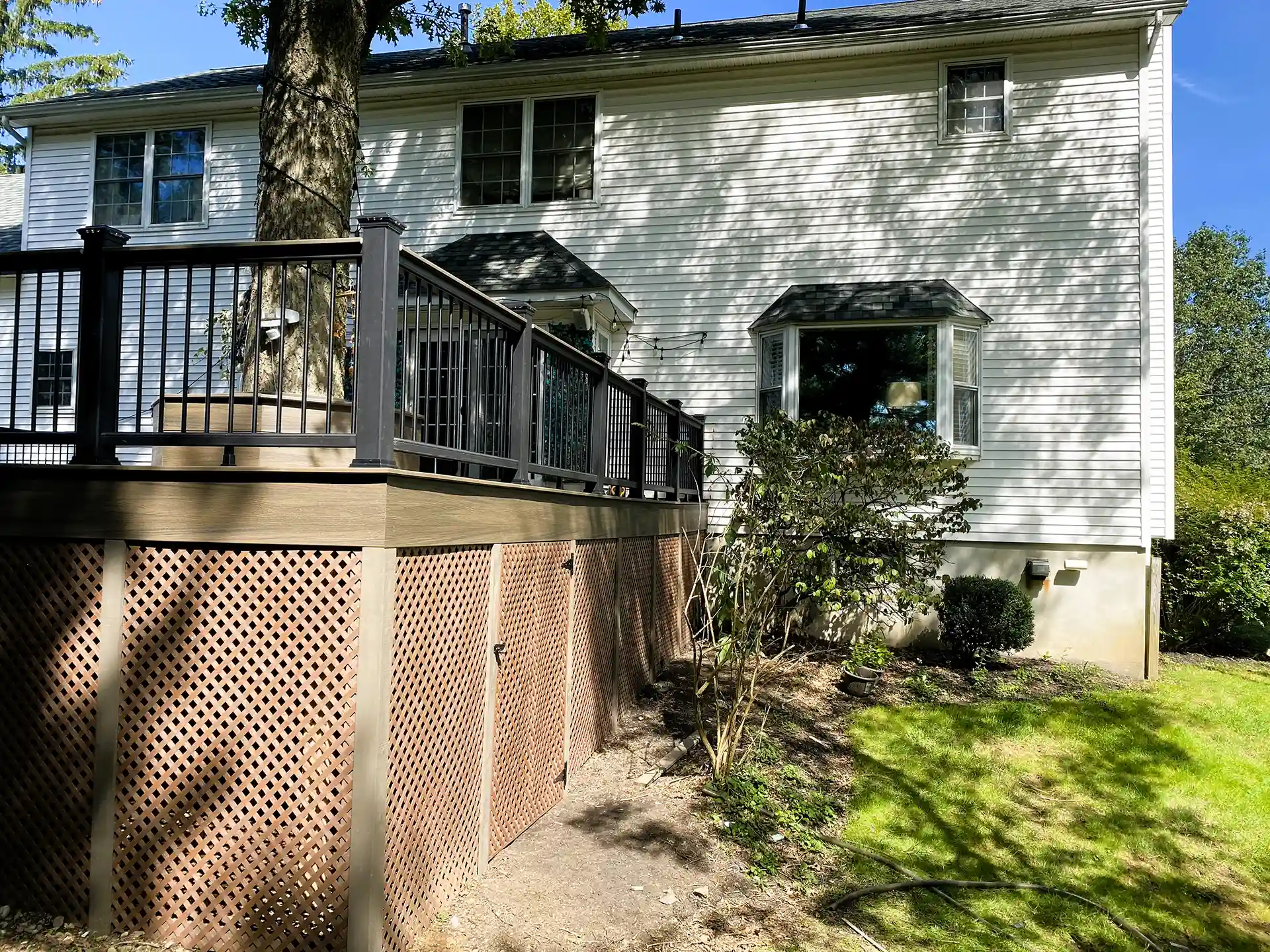 Brown composite deck with white railings, stone steps, and landscaping.