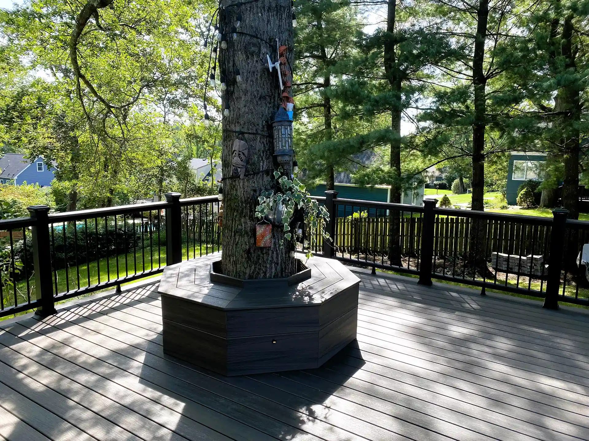 Wooden deck with black railings, built around a tree with a hexagonal base