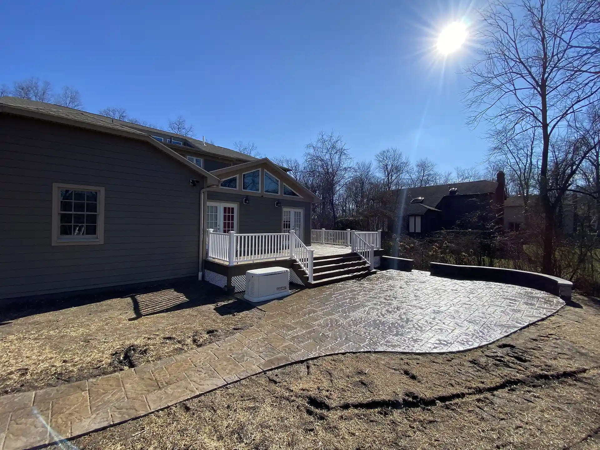 Patio with stamped concrete leading to a deck with stairs.