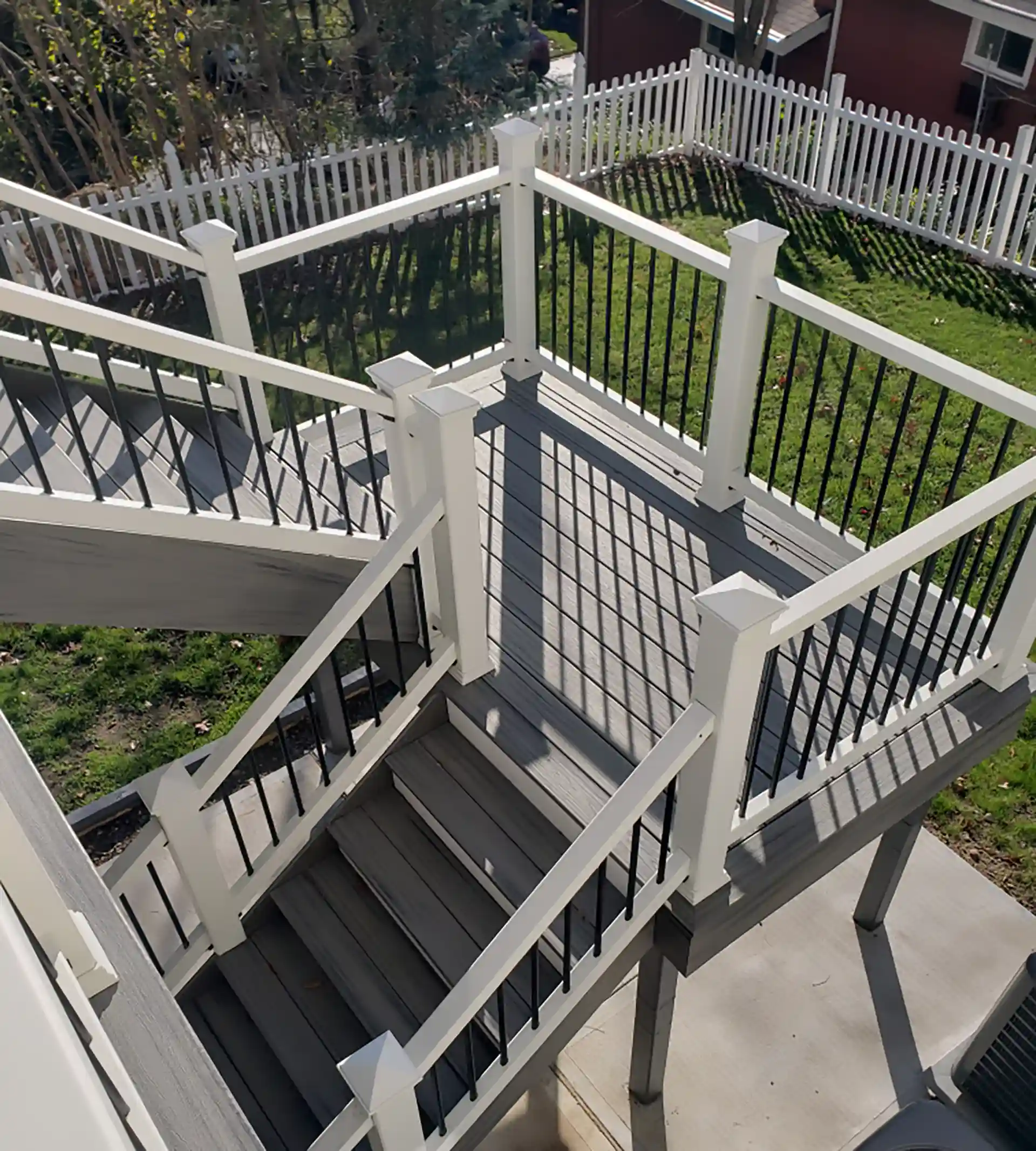 Multilevel composite deck with white railings, black balusters, and connecting staircases.
